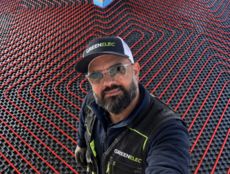 Aziz de Greenelec sur un chantier de plancher chauffant hydraulique, avec les circuits rouges posés au sol.